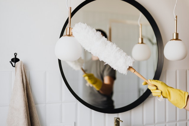 Person cleaning a mirror using a feather duster