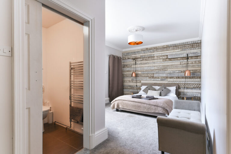 Home en suite,modern,bedroom,with,rustic,wooden,headboard,and,white,linen